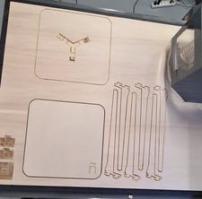 Overview of the full CNC board showing two seat panels with rounded corners, the ñ engraving visible on one panel, and the six leg pieces to the right.