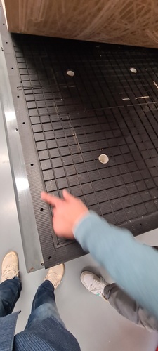 Close-up of the vacuum table surface with a hand pointing at the rubber gasket separating two suction zones.