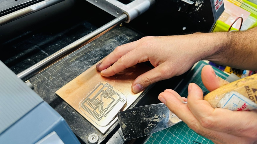 Spatula worked further under the milled board on the MDX-20 bed, lifting it slightly.