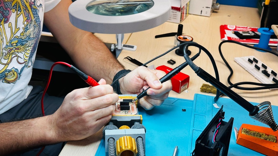 Multimeter probes on assembled PCB checking continuity between pads.