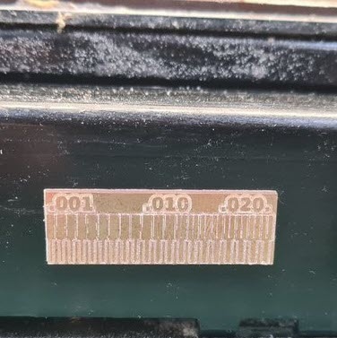 Milled line test board on the MDX-20 sacrificial surface showing three sections of copper traces at 0.001, 0.010, and 0.020 inch clearance, cleanly separated.