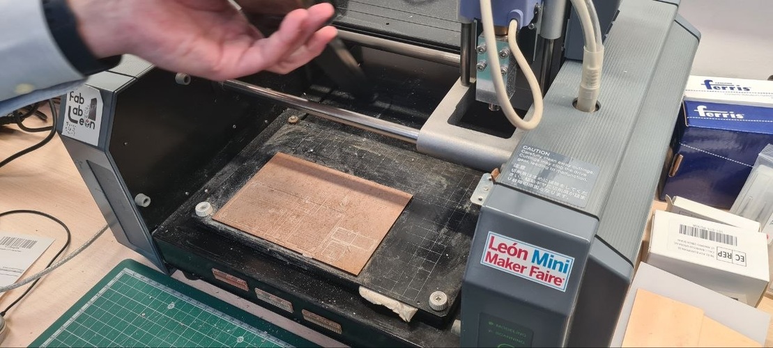 Roland MDX-20 desktop PCB mill with transparent lid open, copper-clad board mounted on the sacrificial surface.