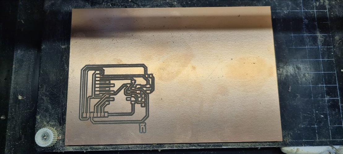 Close-up of copper-clad board in MDX-20 bed showing partial trace isolation completed, copper channels visible.