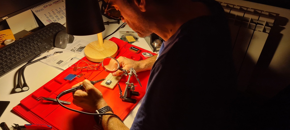 3D-printed PCB vise holding the milled board, blue silicone mat visible in background.