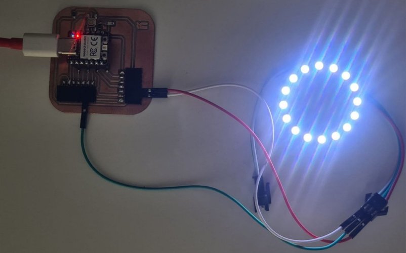 The 16-LED WS2812B ring lit up in blue and white, wired with three jumper wires to the XIAO RP2040 Week 08 board, which is powered over USB-C with its red LED on.