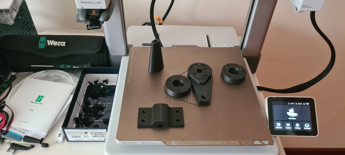 Batch of four black PLA parts on the A1 build plate after a print session, with the touchscreen showing the Print Files menu and the bed temperature at 65 °C.
