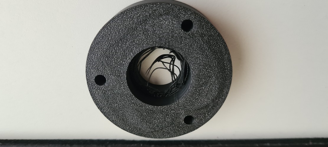 The same batch of parts shortly after, bed at 67 °C, visible defects on the top surface of the triangular bracket at the centre.