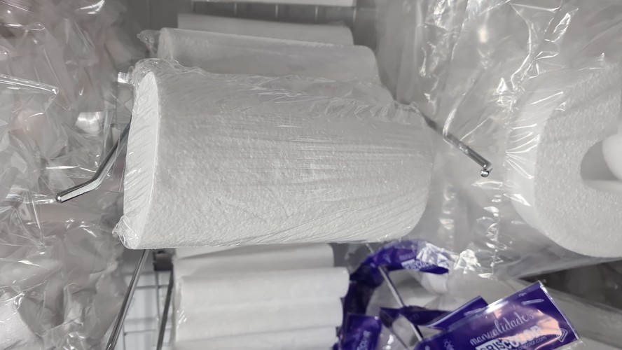 White foam cylinders wrapped in plastic, hanging on a metal display rack at a craft shop.