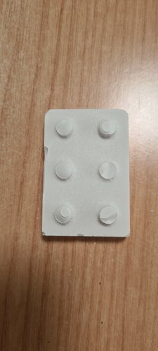 Top-down view of the white plaster cast on a wooden desk, showing the 2x3 grid of six studs. Some studs are well defined, others are visibly shorter or partially incomplete due to trapped air during the cast.