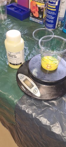 Compostable cup labelled 'B' with yellow Hardener B silicone on the kitchen scale. Display reads 30 g. The Hardener B bottle (yellow liquid) sits next to the scale.