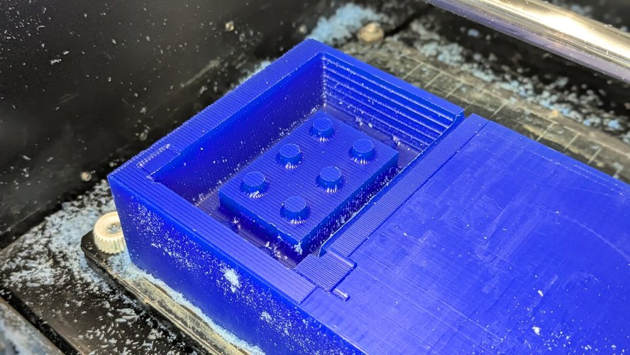 Top-down view of the wax master after the finish pass in XY direction. The brick top and the area around each stud now show the parallel raster lines left by the 3 mm flat endmill — a finer surface than the rough left.