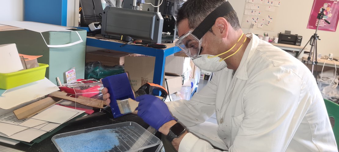 Photo of me with PPE brushing wax dust off the master with a soft brush, before applying release agent.