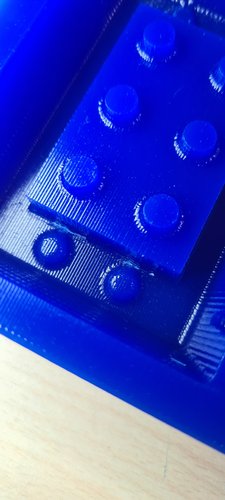 Macro photo of the wax master after manual cutter finishing. The corner studs now have cleaner profiles. The whole master surface is glossy from the release agent.