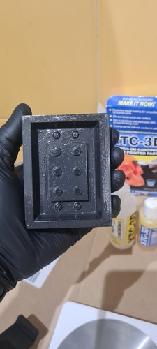 Gloved hand holding the freshly coated PLA master, its surface wet and glossy with XTC-3D. The Smooth-On XTC-3D box and the two bottles, Part A and Part B, are visible in the background.