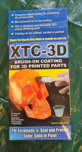 Smooth-On XTC-3D box, blue and yellow packaging, showing an orange skull 3D-print being brushed with the coating. Net weight 6.4 oz (181 g).