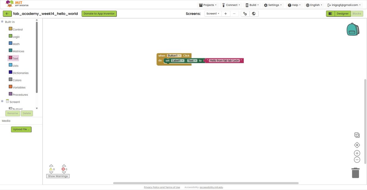 App Inventor Blocks mode after assembly. The three blocks are now connected: 'when Button1.Click do' wraps around the 'set Label1.Text to' block, which itself is followed by the red string block reading 'Hello from fab lab León'. The shapes interlock cleanly, the canvas shows zero warnings and zero errors at the bottom.