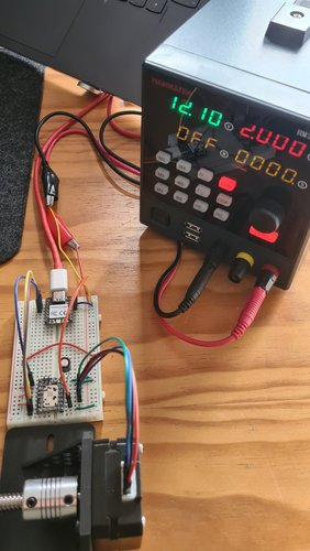 Bench test of one leg's electronics: a XIAO RP2040 on a breadboard, wired to a TMC2209 driver also on the breadboard, driving a NEMA 17 motor coupled to a TR8 lead screw via a flexible coupling. Power comes from a Hanmatek bench PSU set to 12.10 V.