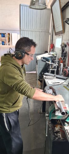 Me cutting one of the PVC pipes to length with an angle grinder, wearing hearing protection and safety glasses.