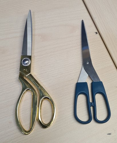 Two pairs of scissors side by side: a large gold fabric pair and a smaller blue paper pair.