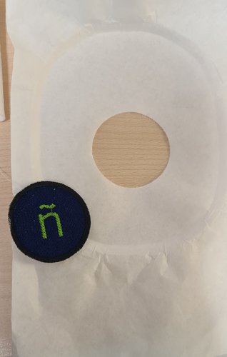 The patch separated, next to the stabiliser sheet with the clean circular hole it left behind.