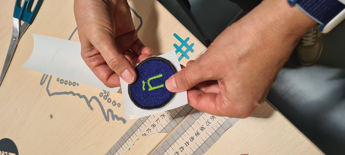 The patch held with the white double-sided adhesive sheet applied to its back.