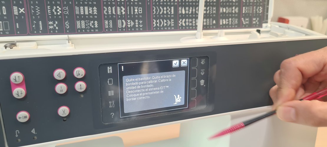 Calibration dialog in Spanish asking to remove hoop and arm, disconnect IDT, fit the embroidery foot.