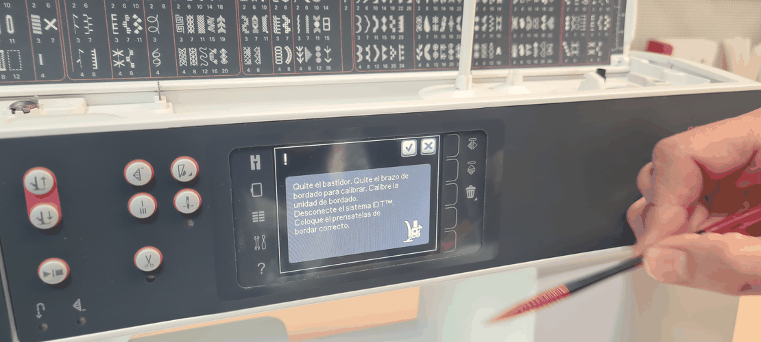 Calibration dialog in Spanish asking to remove hoop and arm, disconnect IDT, fit the embroidery foot.