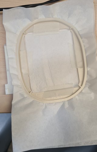 3D-printed 80x80 embroidery hoop on top of stabiliser, fixed with masking tape, arm clip on the left.