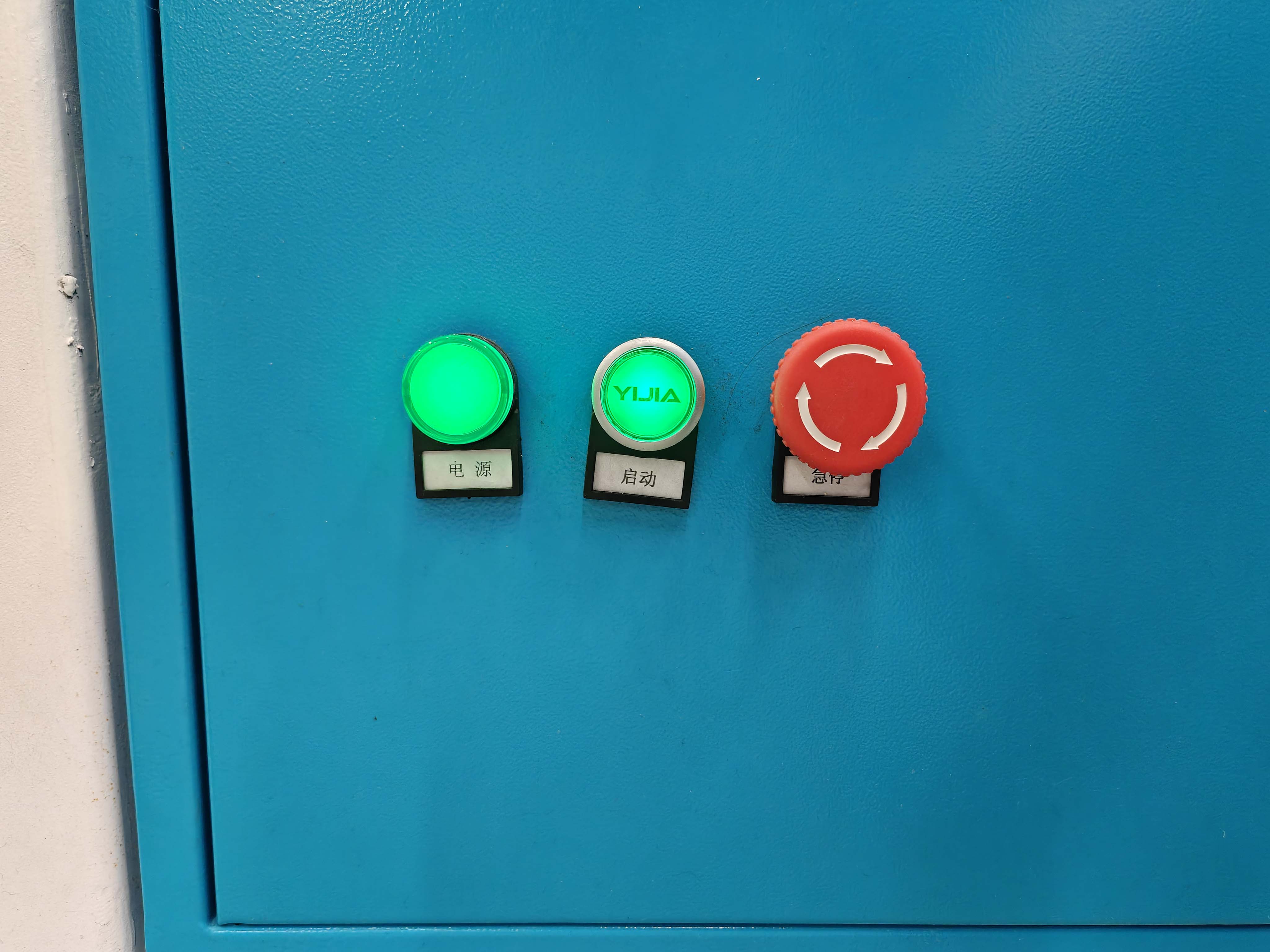 Power start and emergency stop buttons on the CNC machine