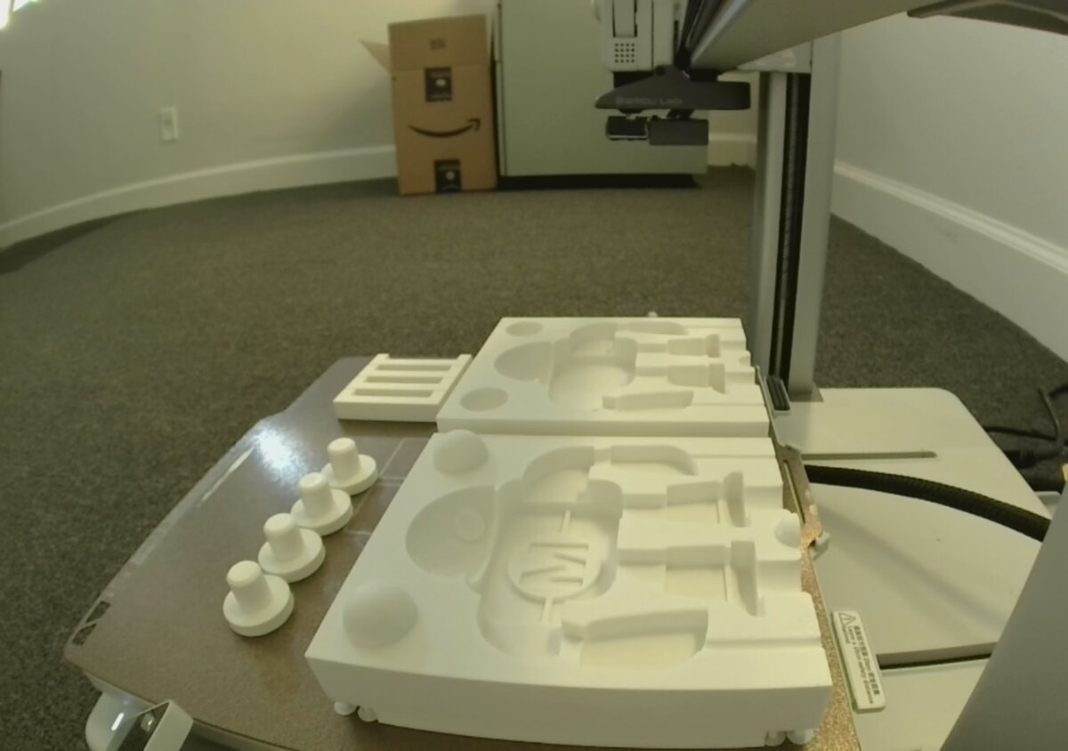 3D printed mold halves and registration pins on table next to printer