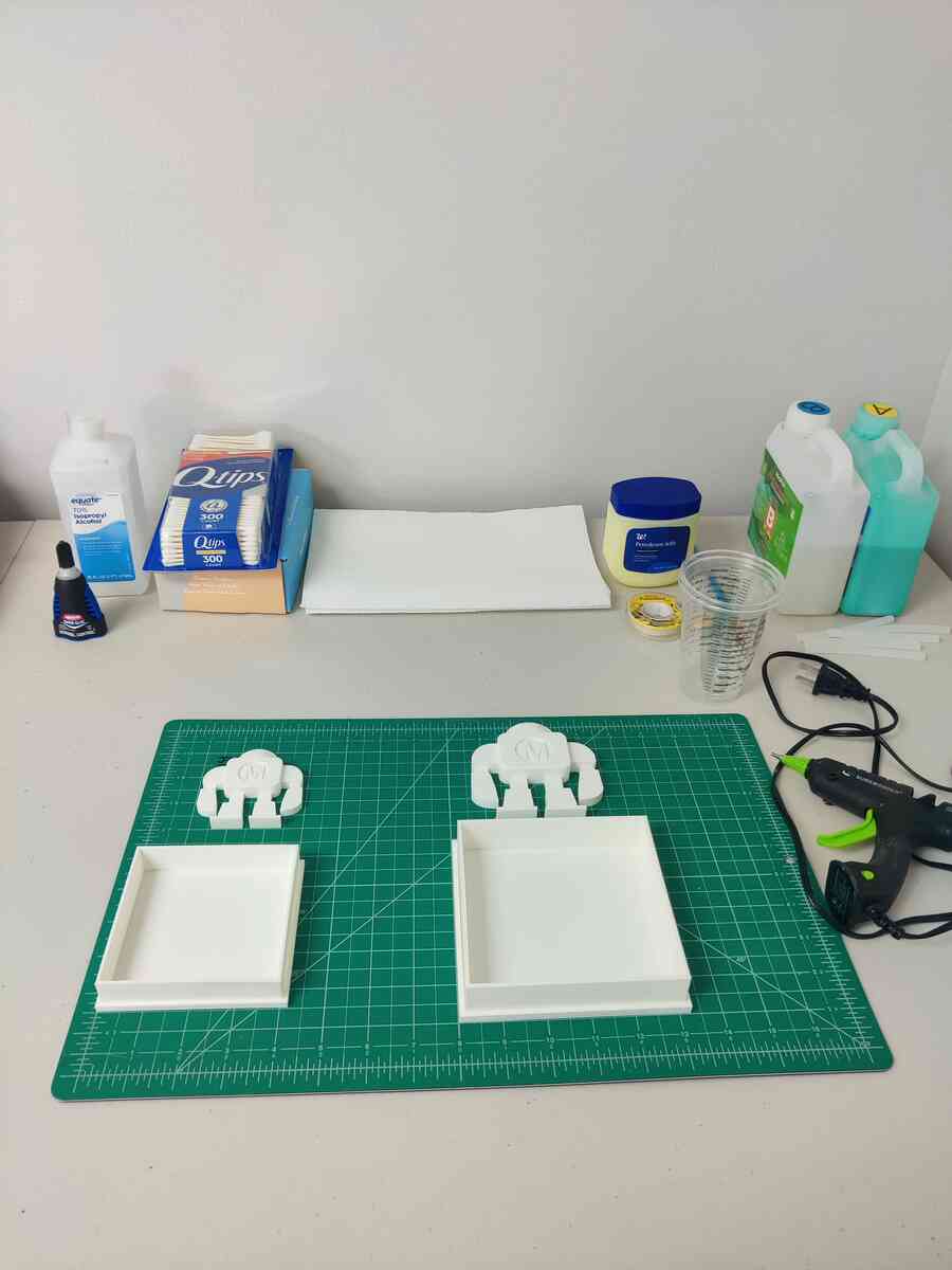 Workspace with mold boxes, isopropyl alcohol, Q-tips, petroleum jelly, silicone rubber, and hot glue gun