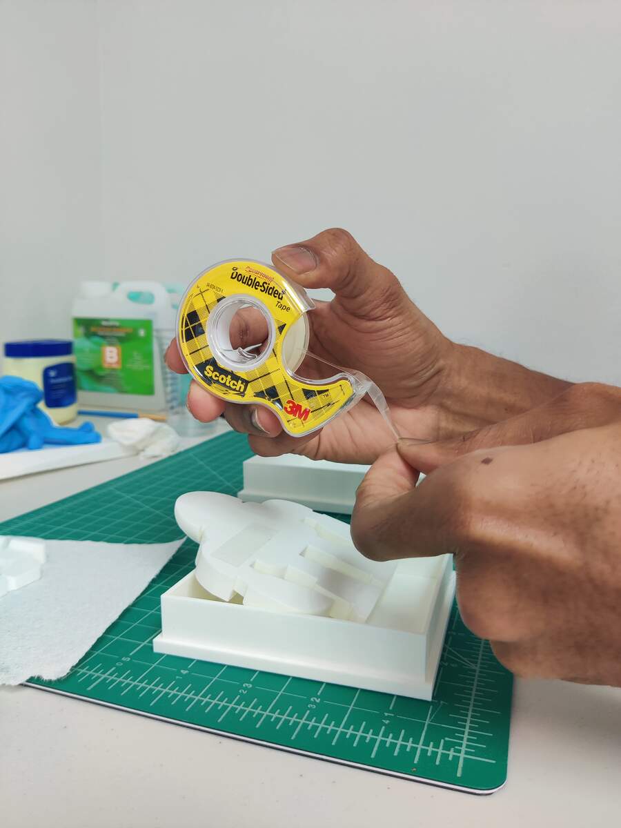 Applying double-sided tape to the robot positive inside the mold box