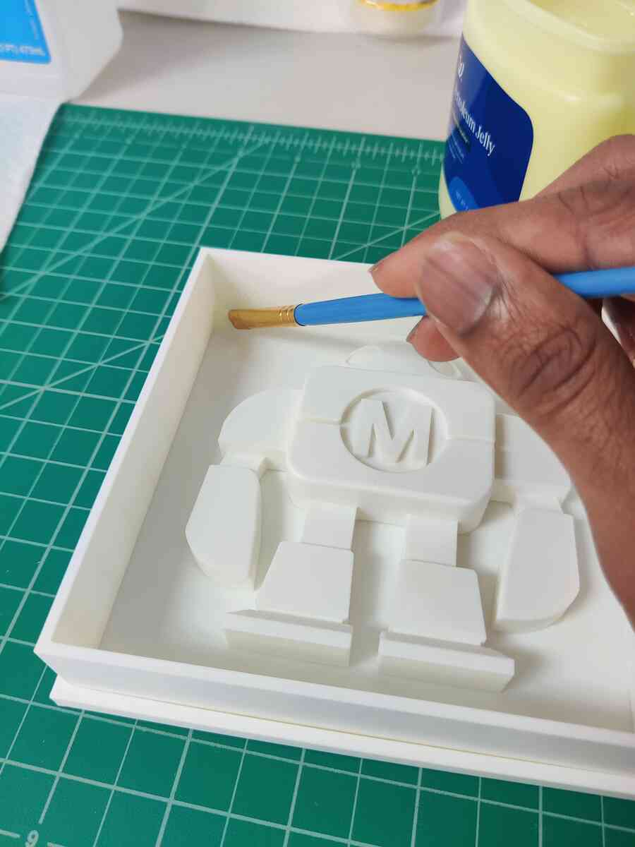 Brushing petroleum jelly onto the robot positive inside the mold box