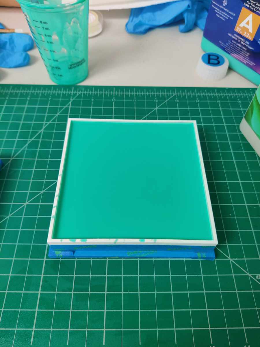 Mold box filled with teal mixed silicone rubber, curing