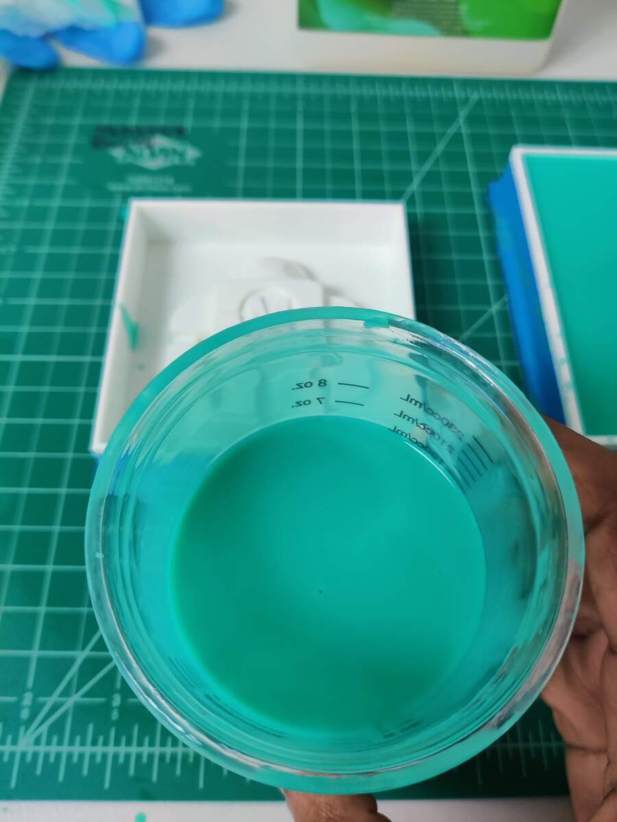 Close-up of teal silicone in the mixing cup being poured