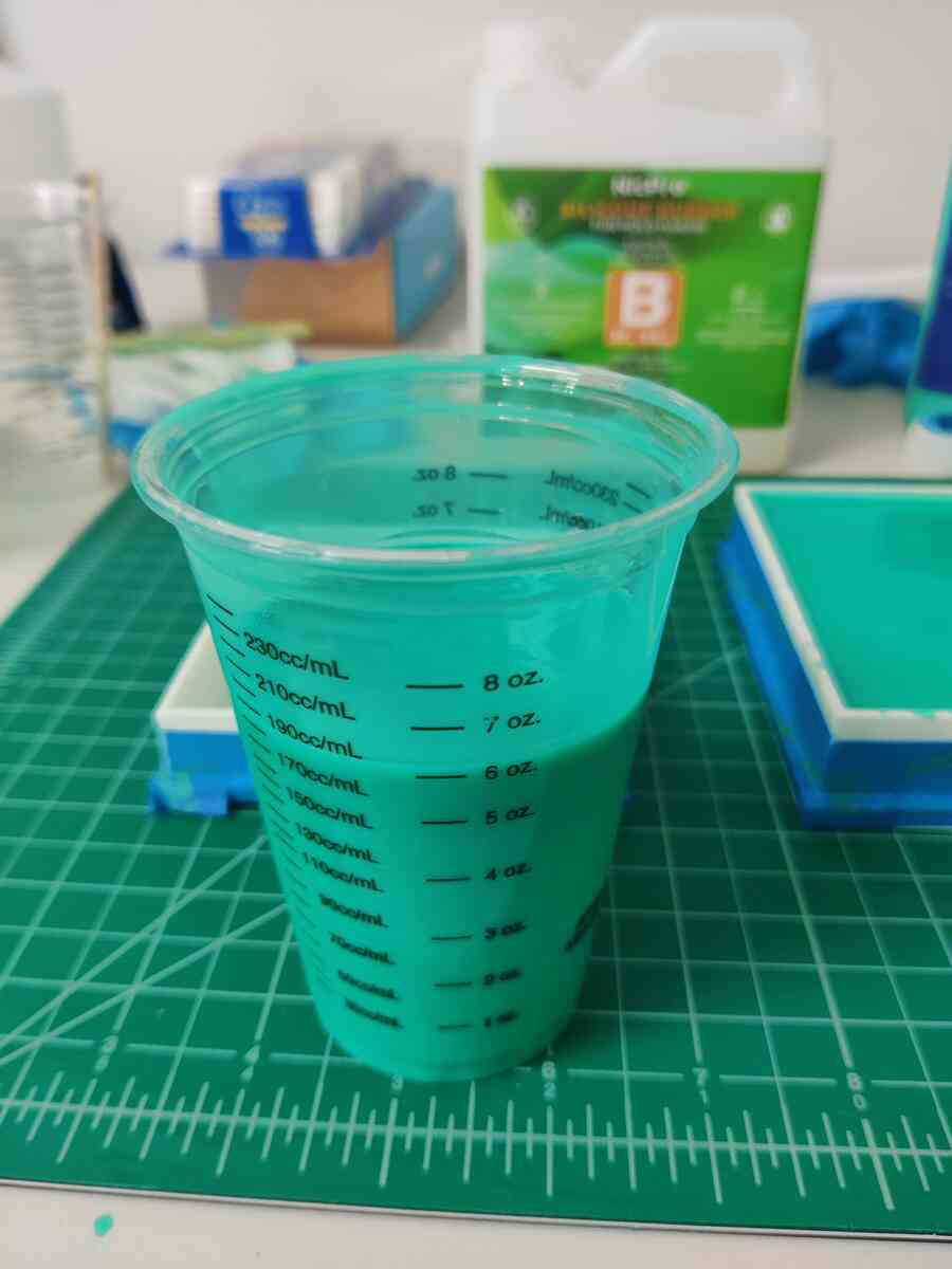 Full measuring cup of mixed teal silicone rubber showing the 6 oz level