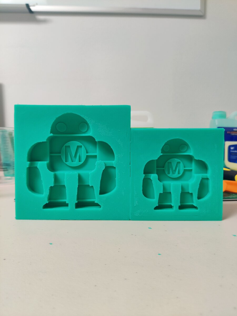 Two completed teal silicone molds showing the robot cavity, large and small