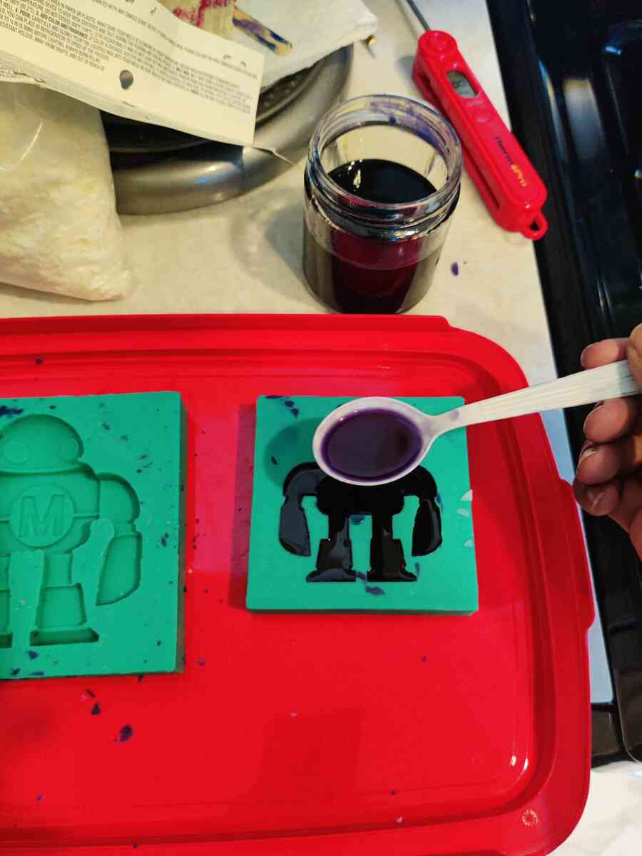 Spooning purple liquid soap into the mold cavities for second attempt