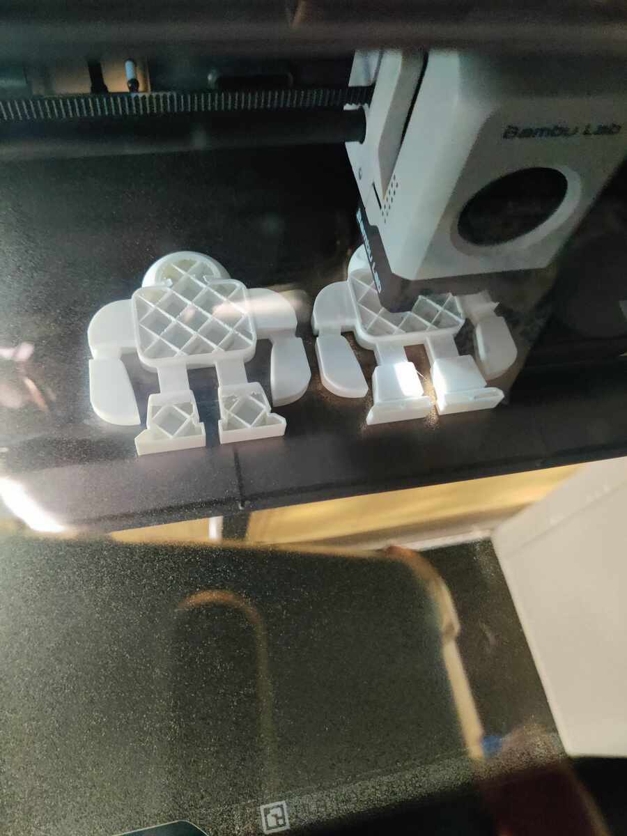 Bambu Lab printer printing two robot positives with grid infill