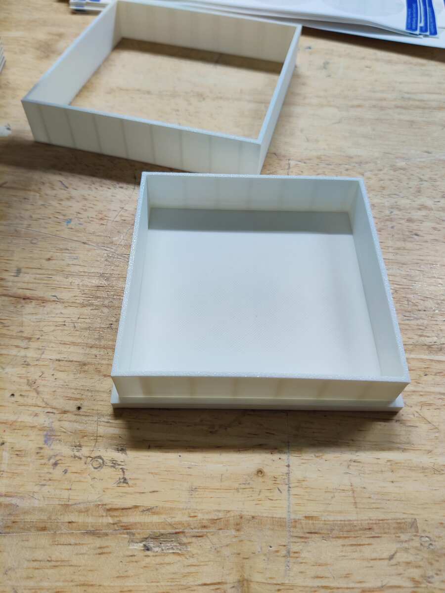 Two completed 3D printed square mold box frames on a workbench