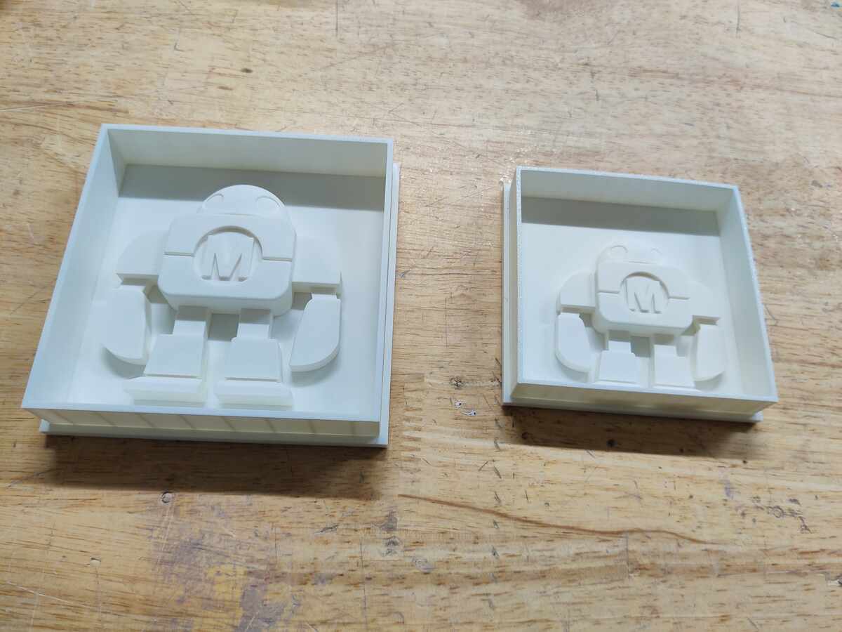 Two assembled mold boxes with robot positives inside, large and small sizes