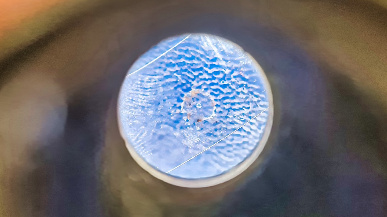 Tape under magnifying glass — beam hole should be centered