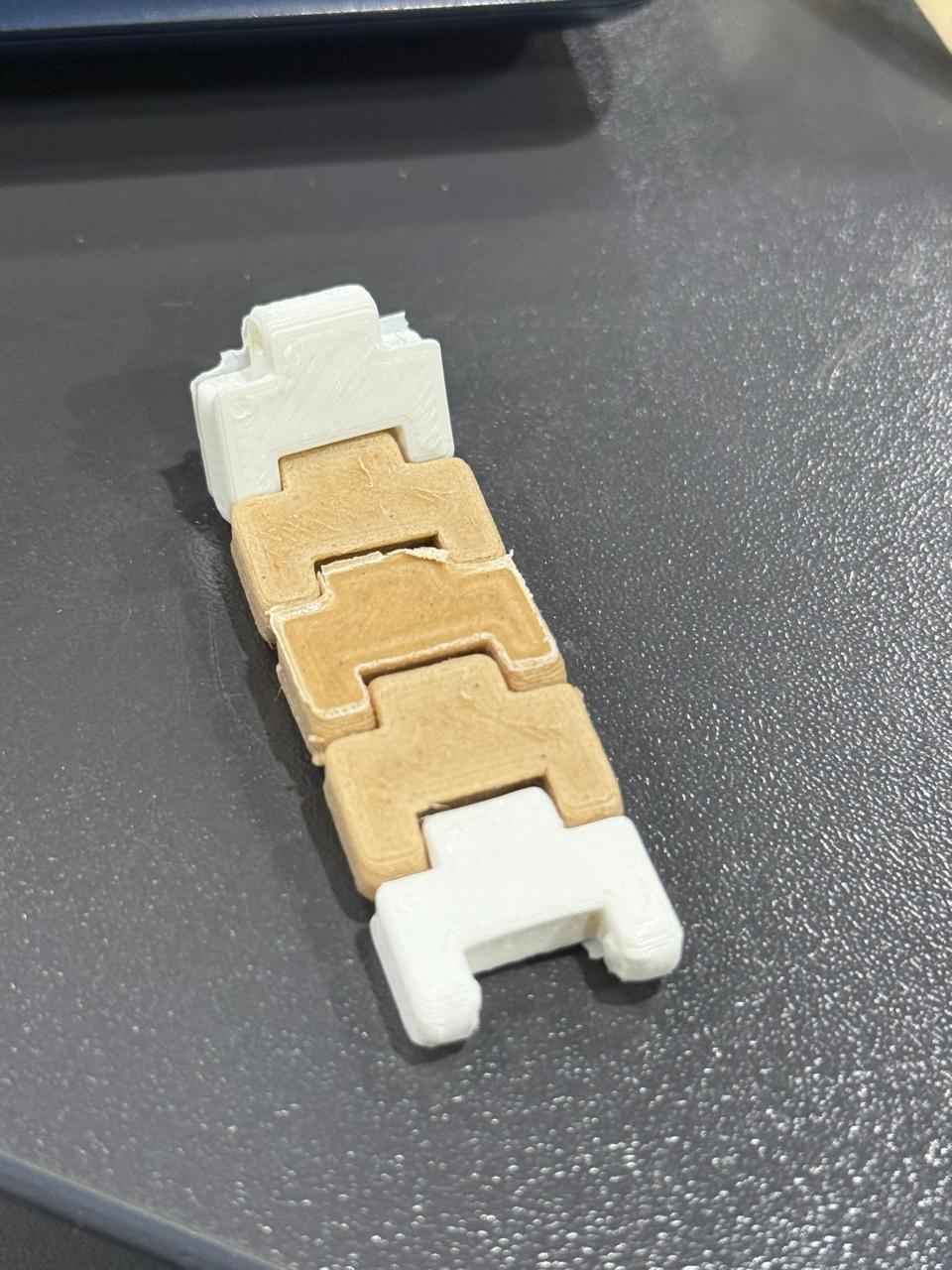 The completed multi-material, flexible interlocking link assembly successfully printed and removed from the build plate.