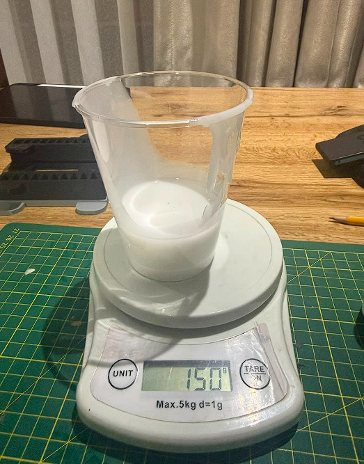 Digital scale showing 150g silicone in mixing cup