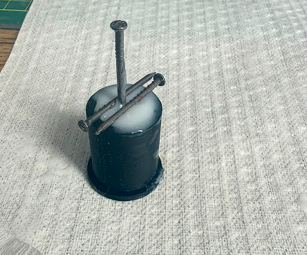 Black PLA cap support with two nails inserted