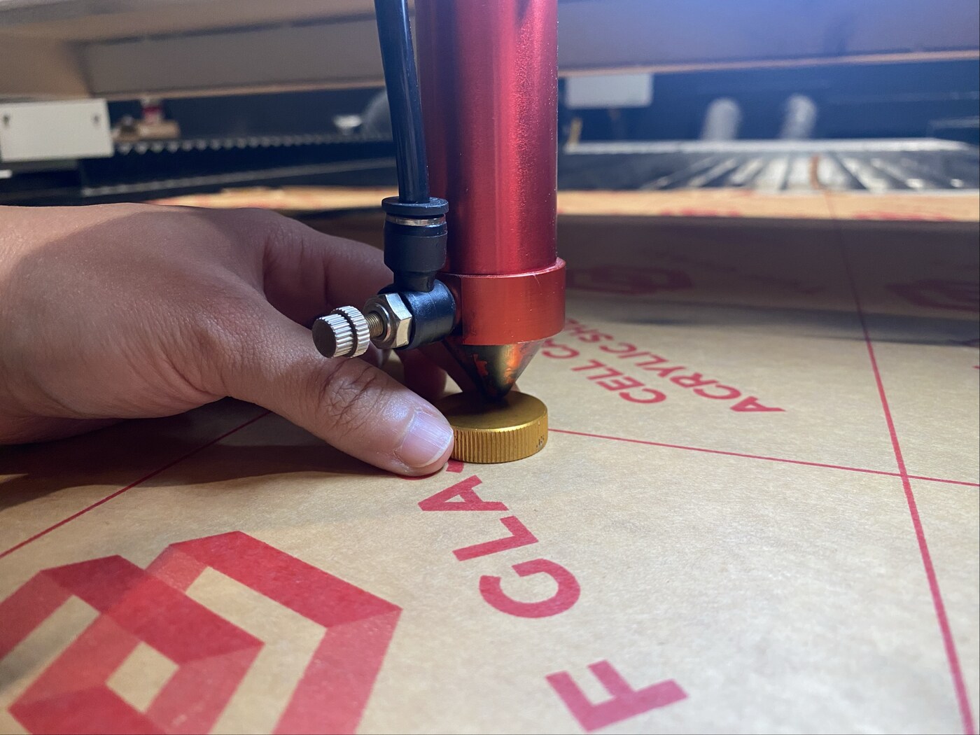 Adjusting the laser cutter nozzle height above the acrylic sheet on the bed