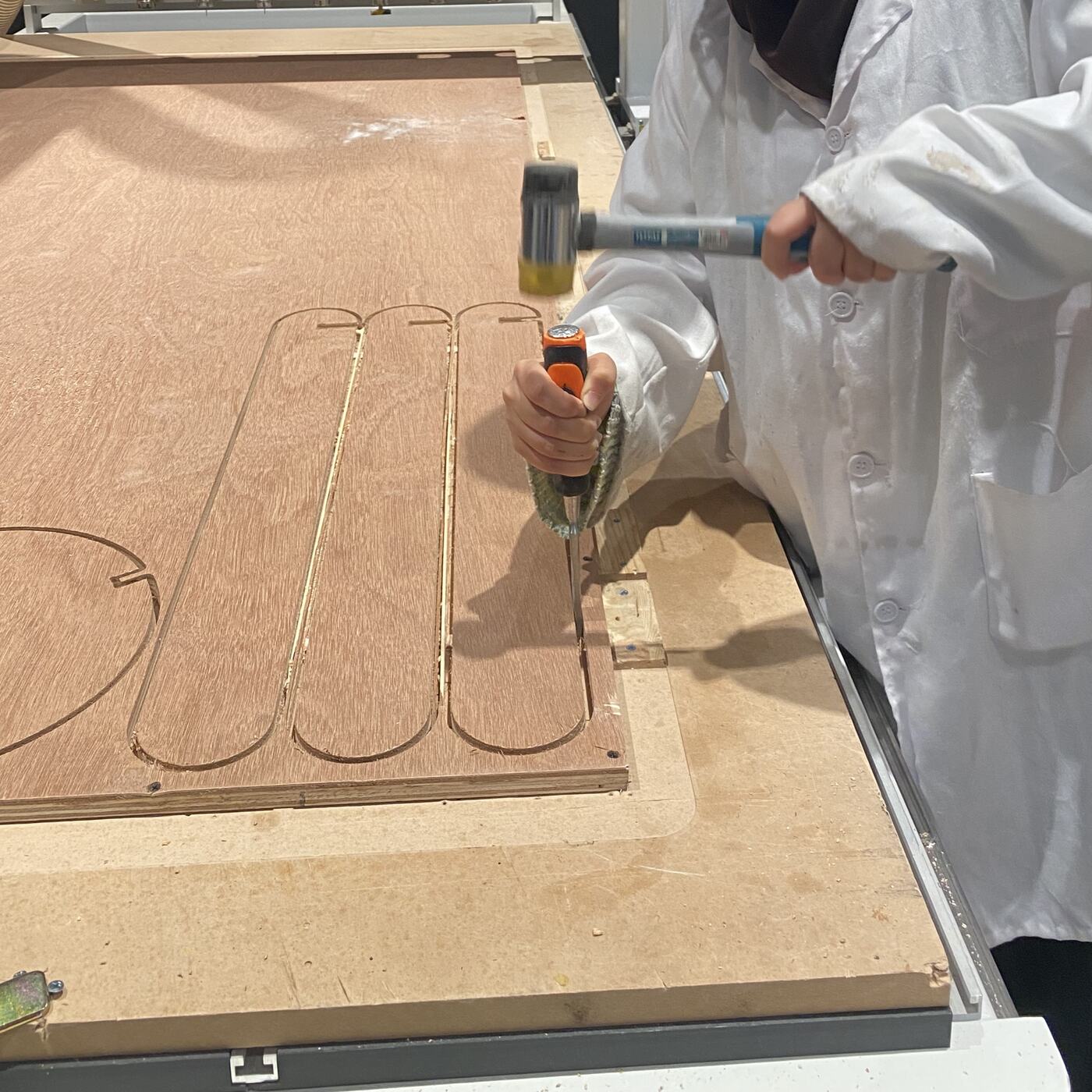 Using a chisel to break the small tabs that held the parts to the plywood sheet