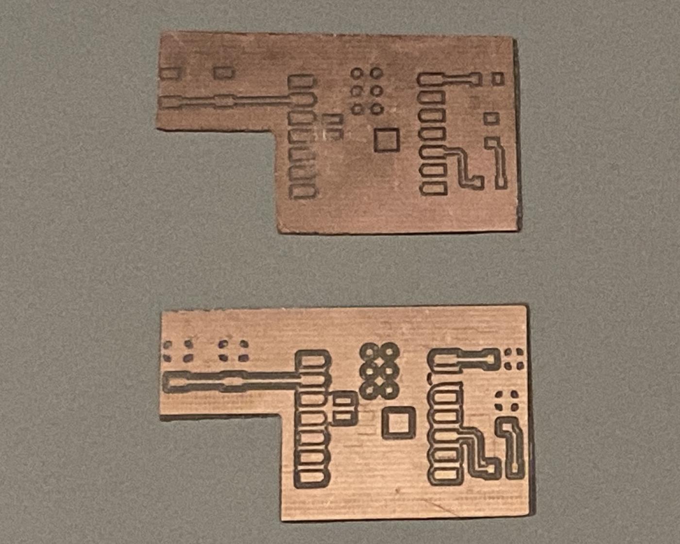 Two milled PCBs — top shows first attempt with alignment error, bottom shows corrected re-mill