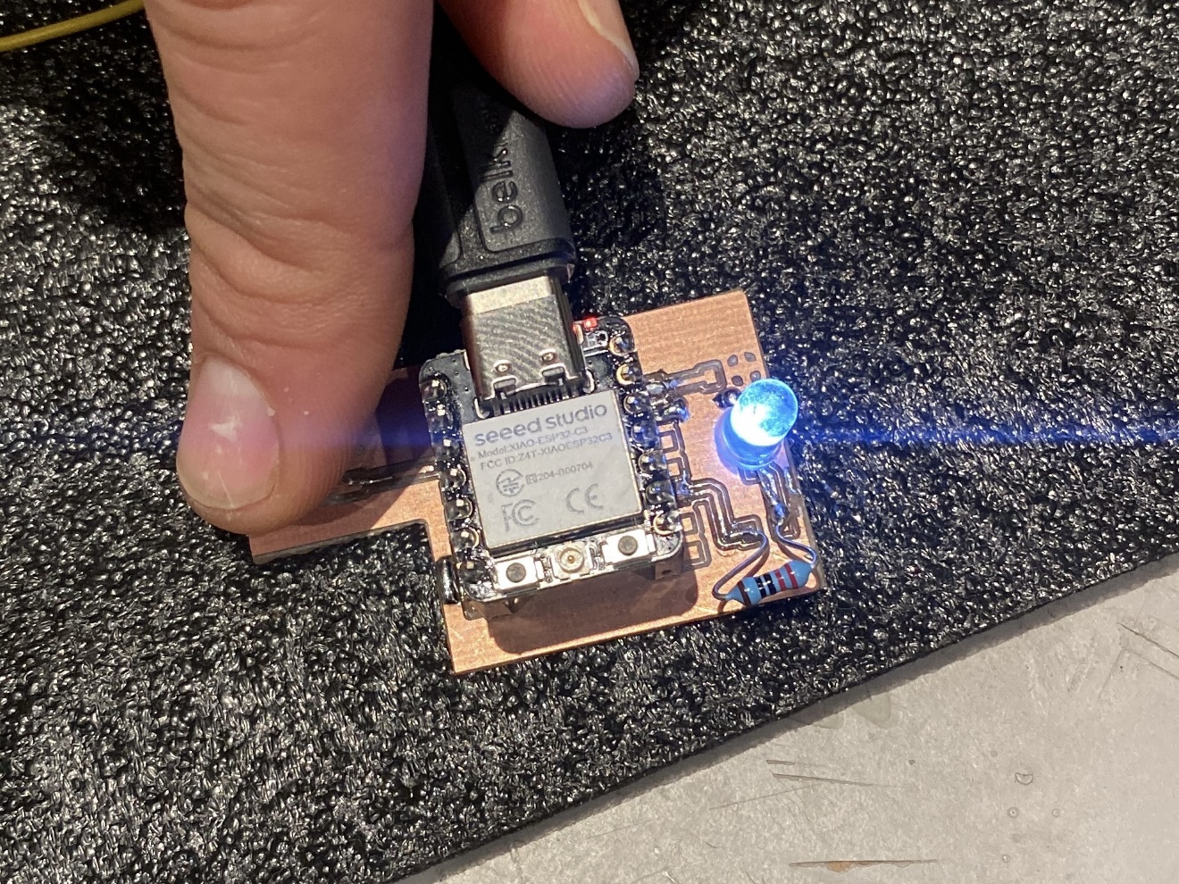 The completed board with the LED lit — button being held down