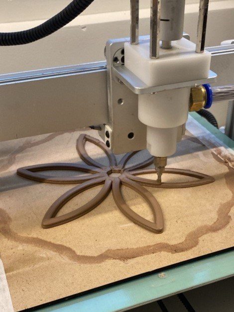 The Tronxy Moore 2 Pro printing the flower base in clay onto a wooden board